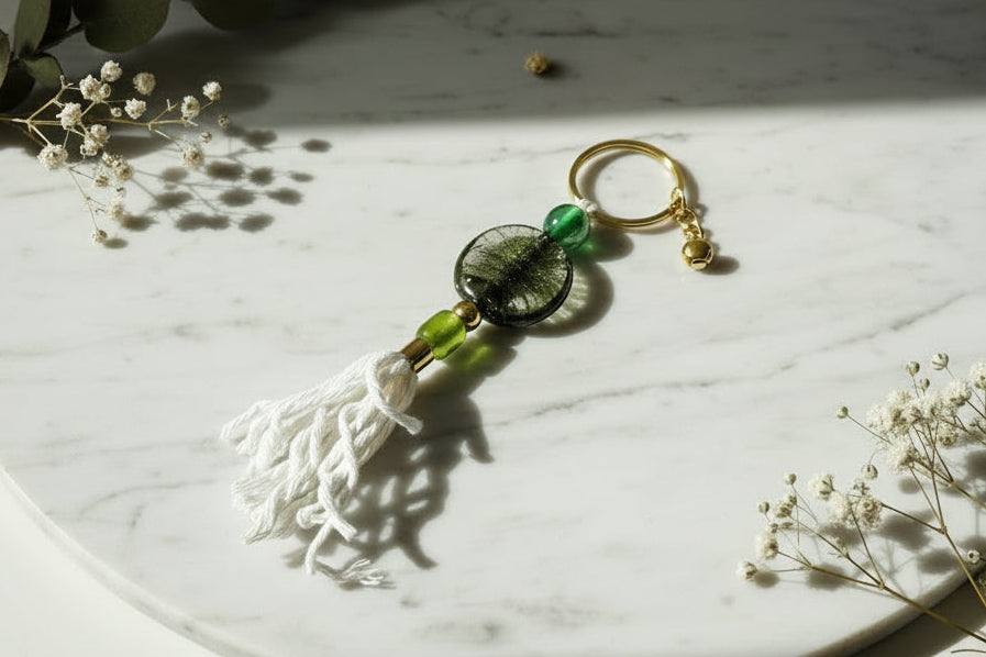 Keychain with green beads on a marble surface with dried plants