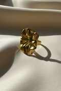 Gold ring on a light beige surface with soft shadows