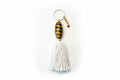 Keychain with glass foiled bead and white tassel on a light gray background