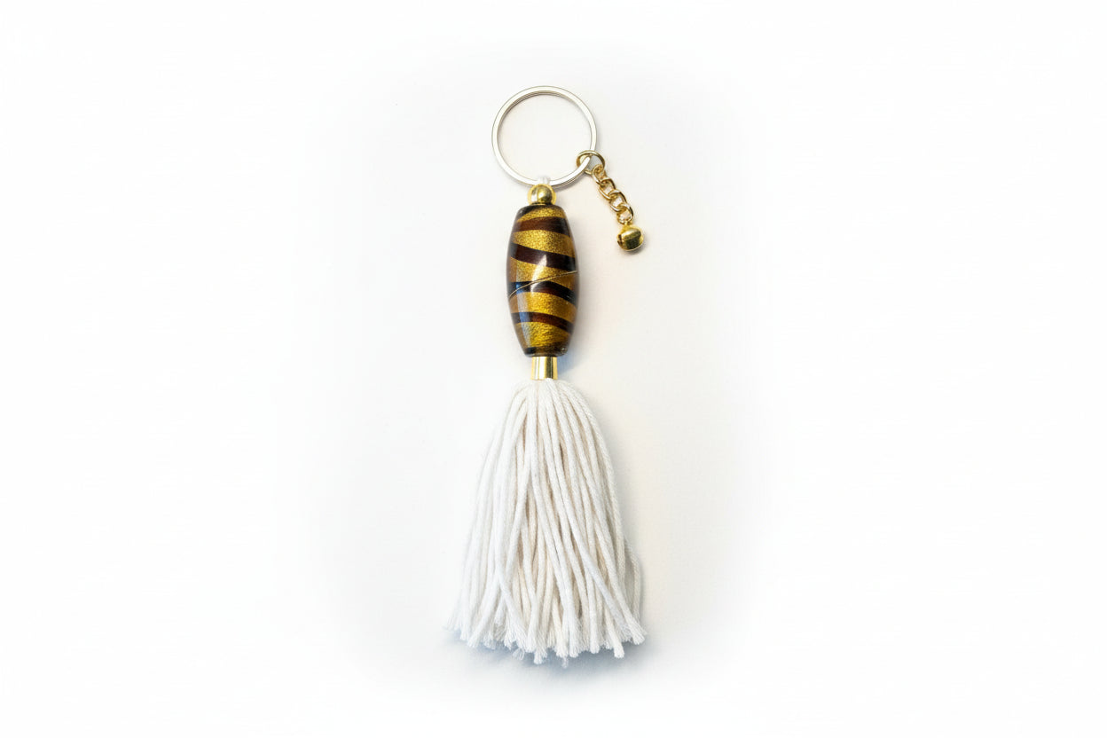 Keychain with glass foiled bead and white tassel on a light gray background