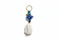 Keychain with blue beads and a white tassel on a light gray background