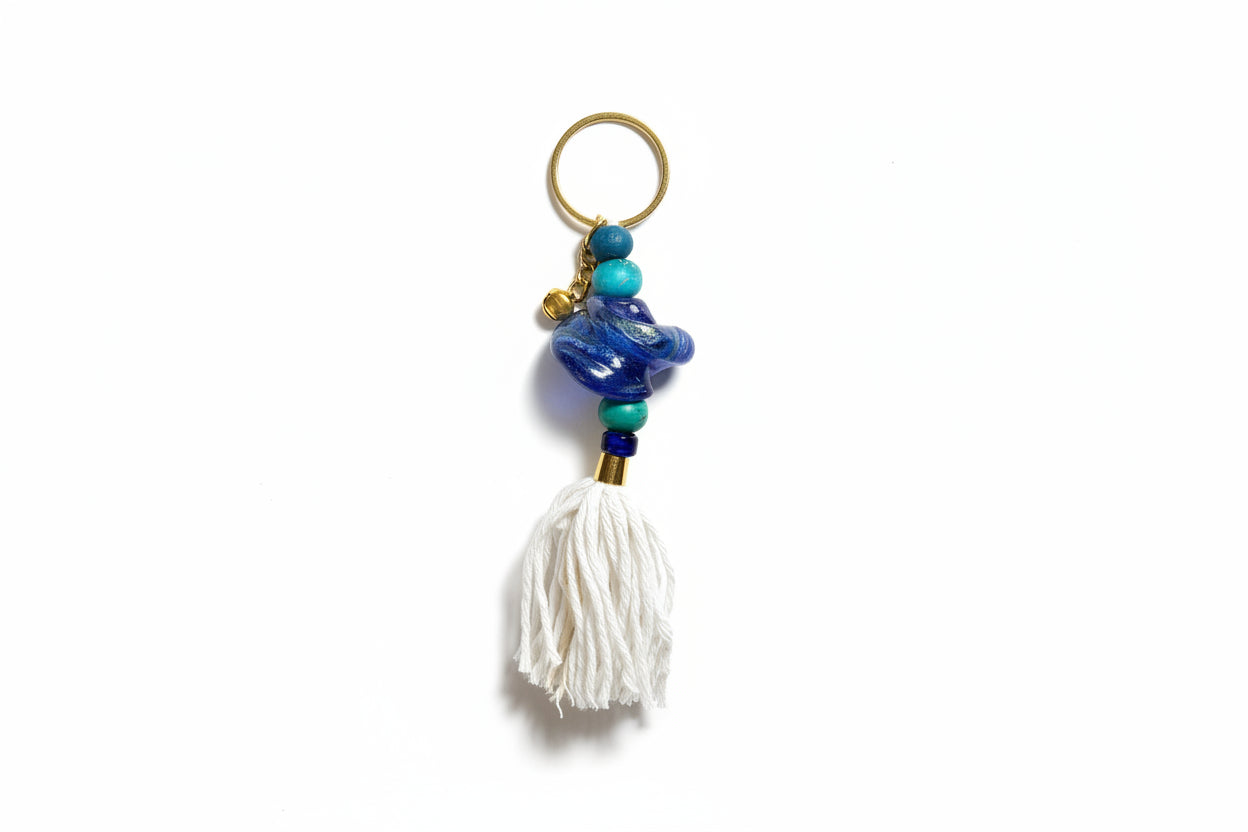 Keychain with blue beads and a white tassel on a light gray background