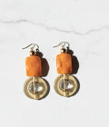 Pair of earrings with orange beads and gold accents on a gray background